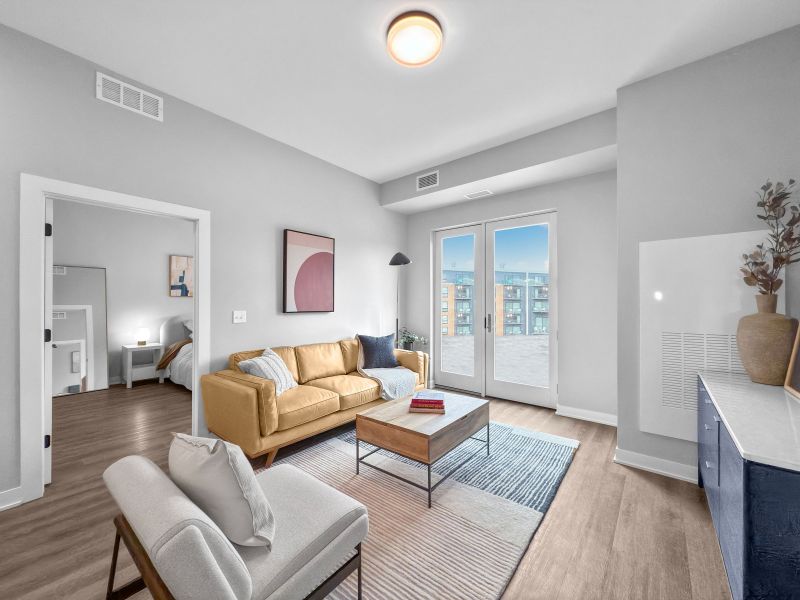 Modern living room at The Meridian with a yellow sofa, cozy armchair, and large glass doors leading to an outdoor view.