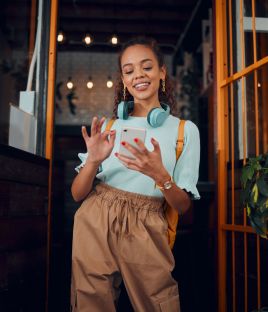 Happy gen z young woman with smartphone, social media fashion influencer in trendy cafe and youth culture in Miami. .Trendy student communication, reading text on cell and 5g technology connection.