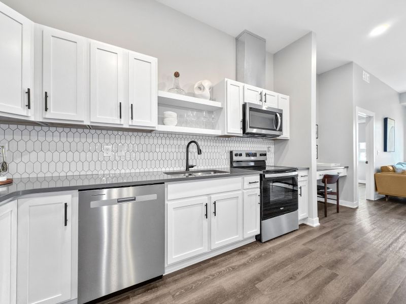 Modern kitchen at The Meridian with white cabinetry, stainless steel appliances, and a hexagonal tile backsplash