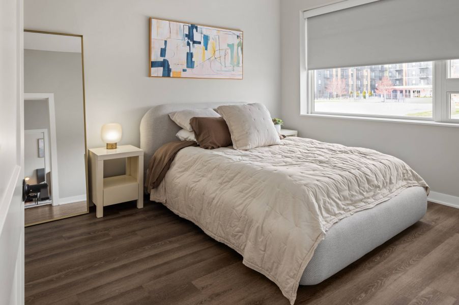 The Meridian apartments spacious bedroom with large window and wood flooring
