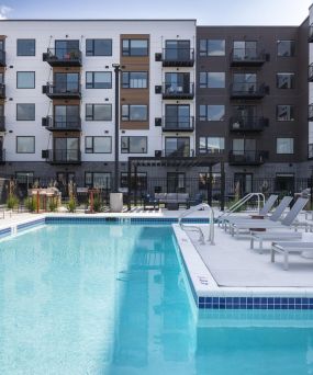 The Meridian outdoor apartment pool with lounge chairs, surrounded by modern multi-story apartment buildings.