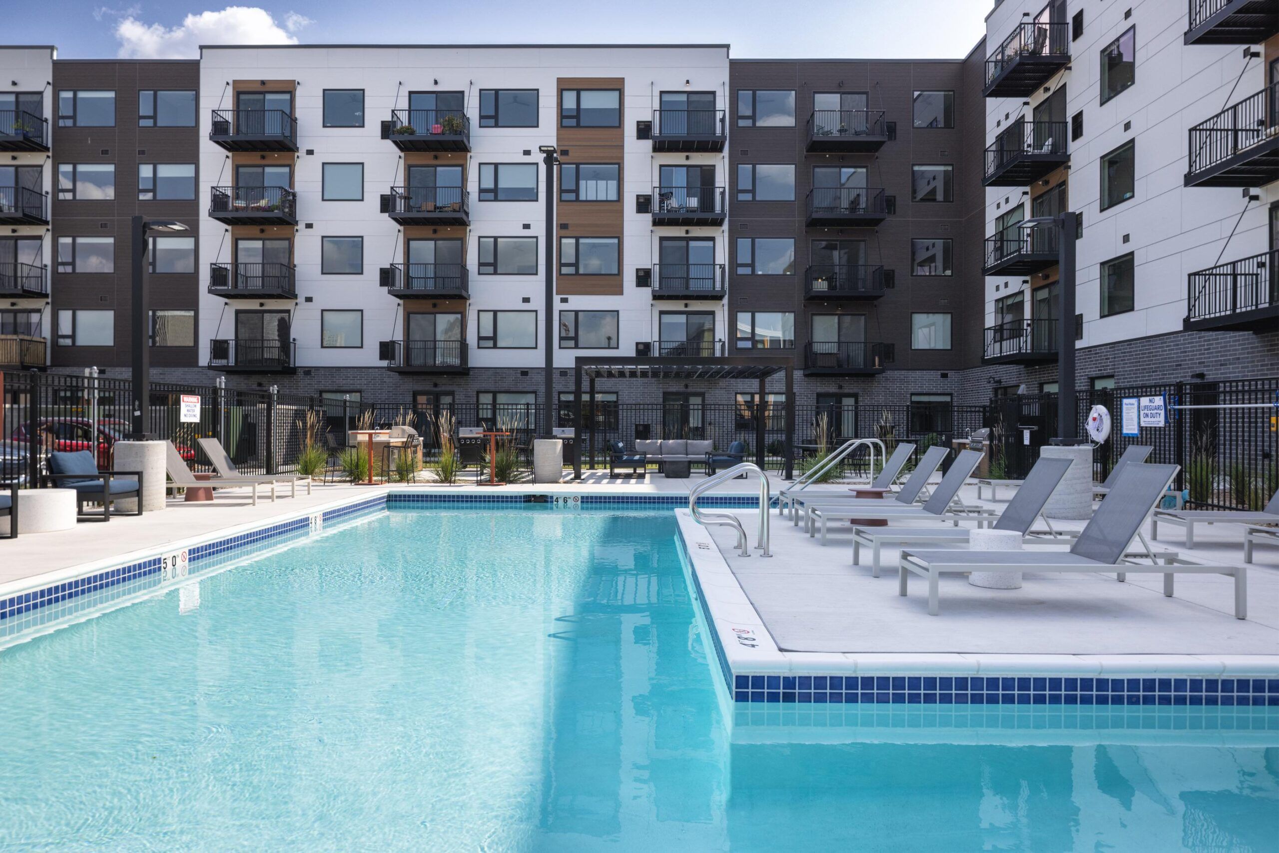 The Meridian outdoor apartment pool with lounge chairs, surrounded by modern multi-story apartment buildings.