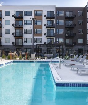 The Meridian outdoor apartment pool with lounge chairs, surrounded by modern multi-story apartment buildings.